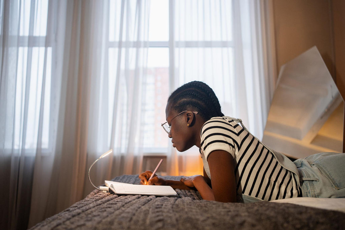 Black woman over 40 sitting on bed at night holding a journal, feeling emotionally exhausted but ready to begin healing and self-care practice