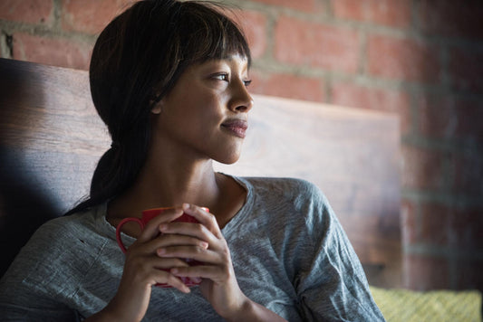 Black woman in her 40s with contemplative expression holding mug representing turning 40 and grief recovery journey