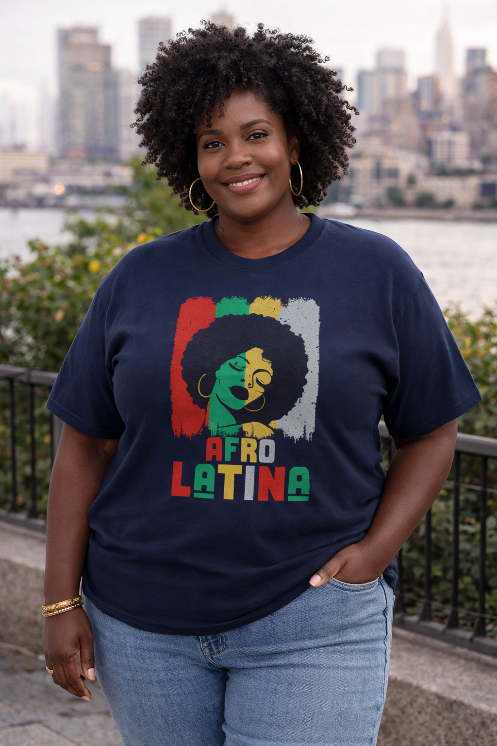 Plus size Black woman in her 40s wearing a navy Afro Latina graphic t-shirt with bold red, green, and yellow afro art design.