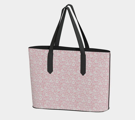 Tote bag with pink floral pattern and black handles on a light gray background